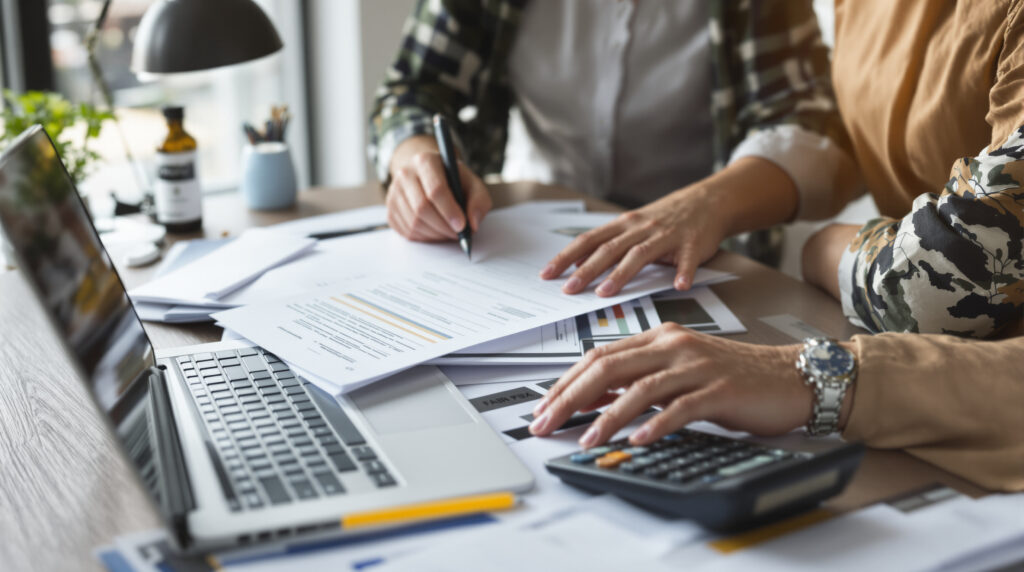 A contractor at a desk using a calculator and laptop to calculate 1099 taxes.