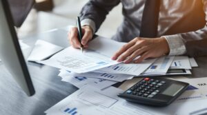 A business owner at a desk developing a tax strategy by reviewing financial documents and using a calculator.